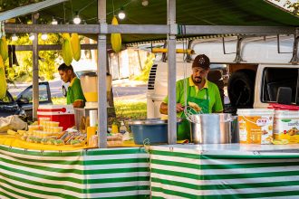 Vendedores preparam pratos à base de milho em uma barraca de comida de rua.